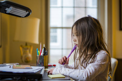 Little multi ethnic girl doing school work at home