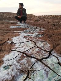 Full length of man sitting on rock