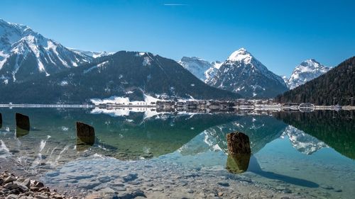 Scenic view of lake by snowcapped mountains against sky