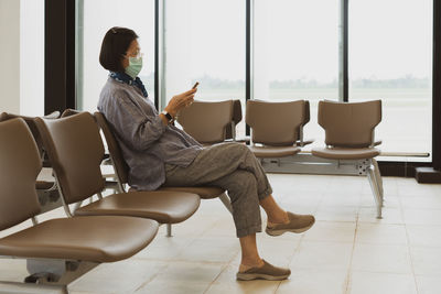 Side view of woman sitting on chair at home