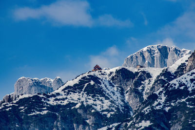 Low angle view of snowcapped mountains against blue sky