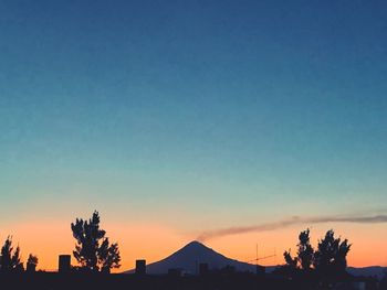 Silhouette trees and buildings against clear sky during sunset