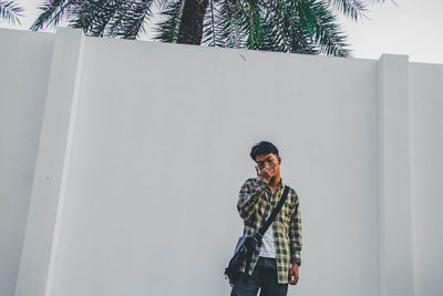 Full length of young man standing against wall