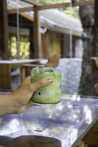 Cropped hand of person holding drink on table