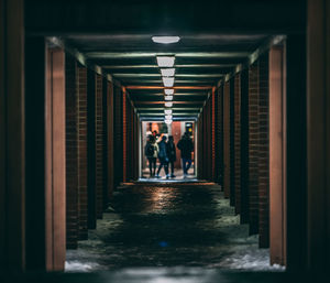 People walking in illuminated corridor of building