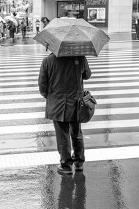 Full length of man with umbrella walking on street