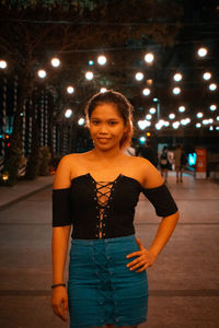 Portrait of smiling woman standing in city at night