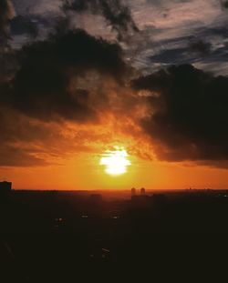 Silhouette landscape against dramatic sky during sunset