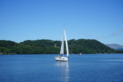 Sailboat sailing on sea against clear blue sky