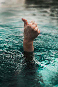Cropped hand of woman gesturing under water