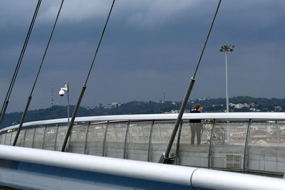 Birds on railing against bridge in city against sky