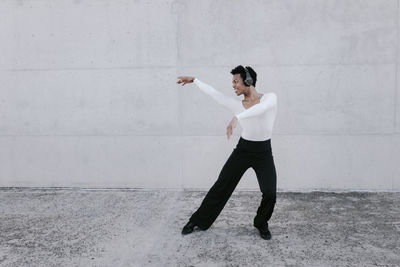 Full length of young woman standing against wall