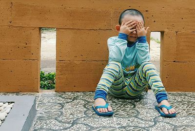 Full length of boy covering eyes with hands while playing hide and seek