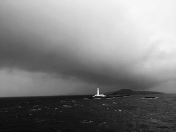 Lighthouse by sea against sky