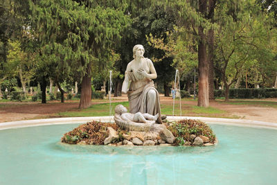 Statue by swimming pool in park