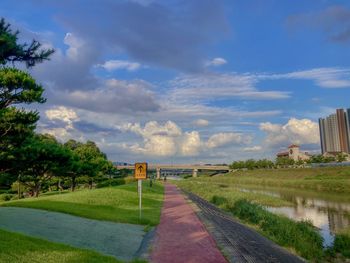 Footpath amidst trees and buildings against sky