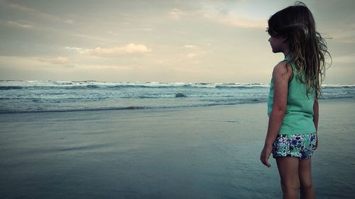 Rear view of girl standing at beach