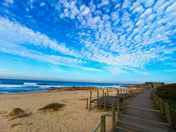 Boardwalk on beach against sky