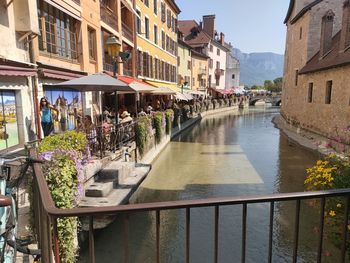 People on canal by buildings in city