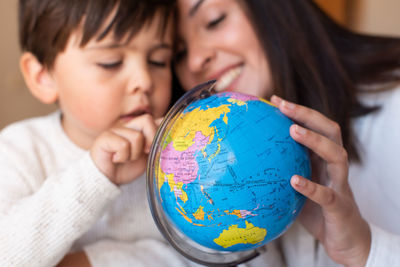 Close-up of mother and son holding globe at home