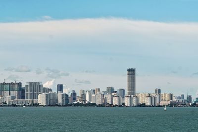 Sea by buildings in city against sky