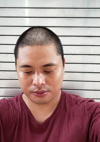 Close-up portrait of a teenage boy with eyes closed against wall