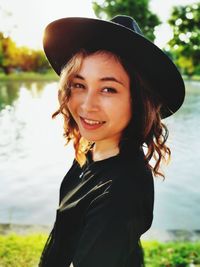 Portrait of smiling young woman in park by lake