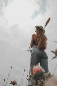 Low angle view of woman with flowers against sky
