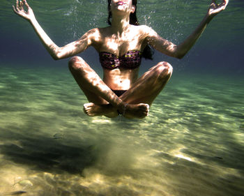 Young woman with crossed-legs floating undersea