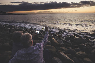 Couple taking selfie from mobile phones at beach during sunset