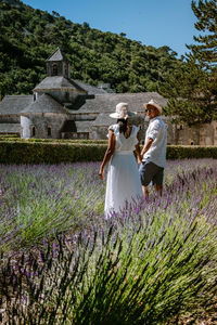 People standing by flowering plants on field