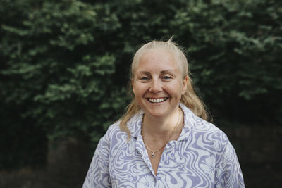 Portrait of happy blonde woman standing outdoors