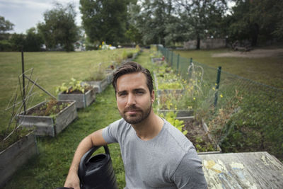 Portrait of mid adult man with watering can in vegetable garden