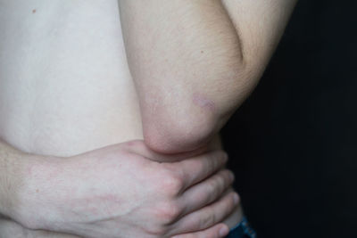 Midsection of shirtless mid adult man with wounded hand against black background