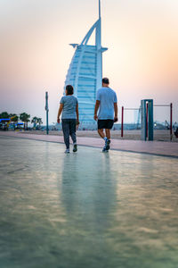 Rear view of people walking on water against sky