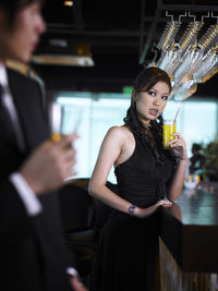 Young woman looking at businessman drinking at bar