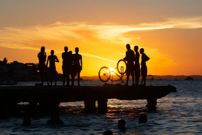 Dozens of young people, in silhouette, are seen on top of the crush bridge having fun. 