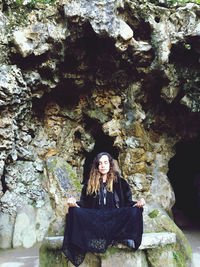 Portrait of young woman sitting on rock