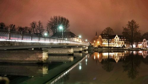 Reflection of trees and building on reflecting pool by bridge