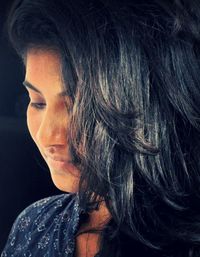 Close-up of woman with hair against black background