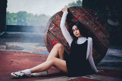 Portrait of young woman leaning on wooden table while sitting on floor