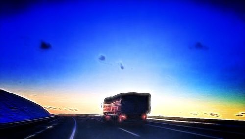 Cars on road against sky at sunset