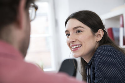 Smiling woman looking at man in office