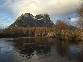 Calm lake in front of rocky mountains against sky