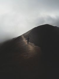 Silhouette person on mountain against sky