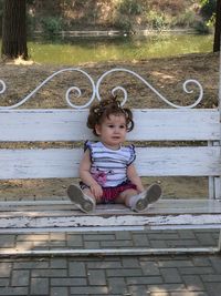 Full length of baby girl sitting on bench at park