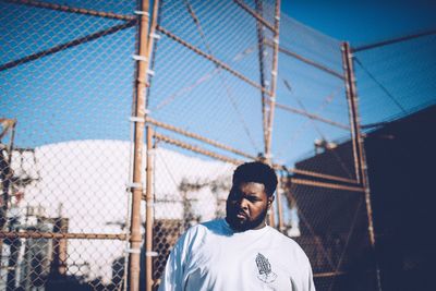Full length of man in front of fence against clear sky
