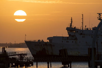 Sunrise in the port of punta de piedras with a backlit ferry and the big orange sun