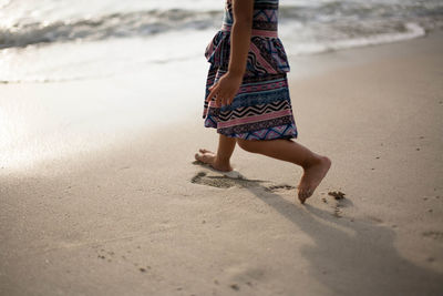 Low section of woman walking on shore at beach