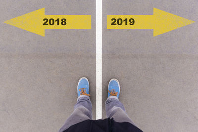 Low section of man standing on arrow sign